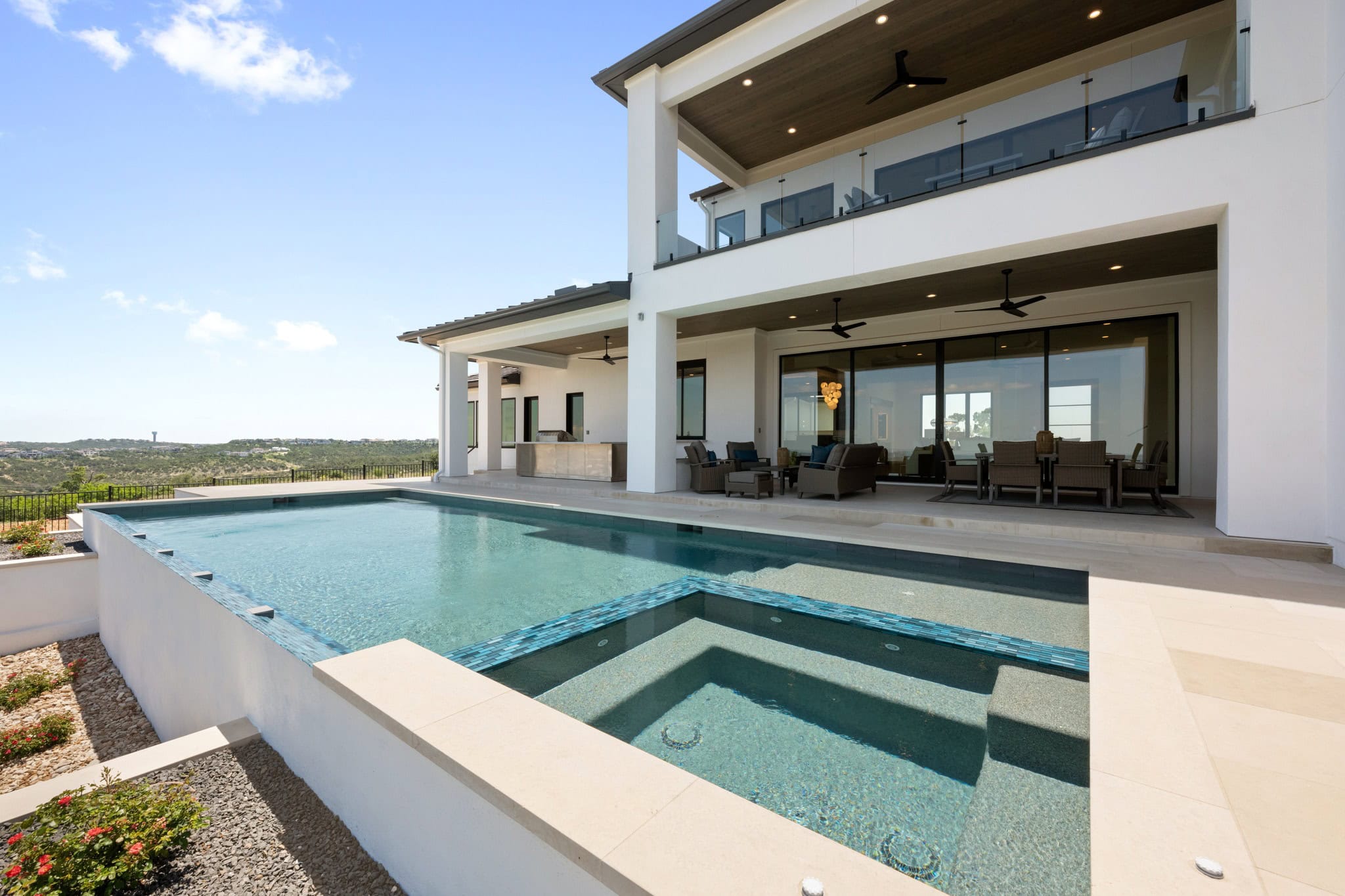 Backyard view of Hilltop Haven, featuring a private retreat with a pool, integrated spa, and lounge beach, as well as a covered patio.